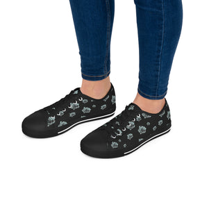 Feet wearing Black Sneakers with silver/blue roses and white soles and laces. 