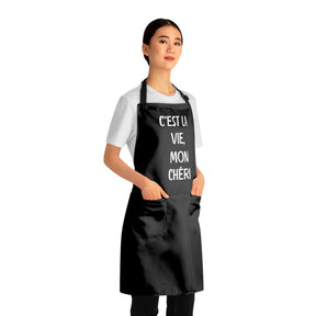 side view of a woman wearing a black grilling apron with black straps with says "c'est la vie, mon chéri"