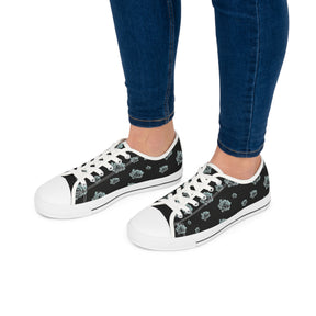 Feet wearing  Black Sneakers with silver/blue roses and white soles and laces. 