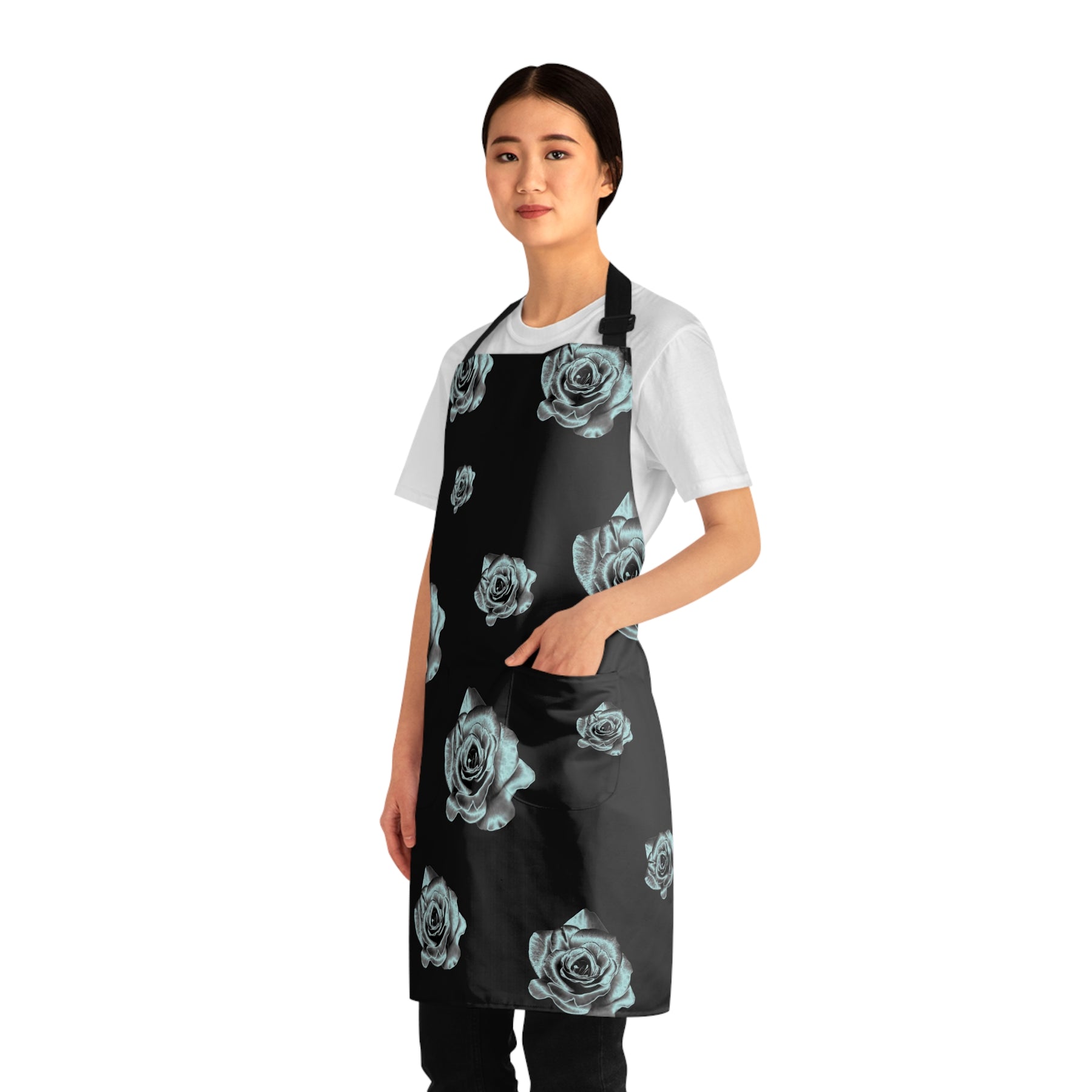 side view of girl wearing a grilling apron with a black and silver rose pattern on it and black straps with her left hand in apron pocket