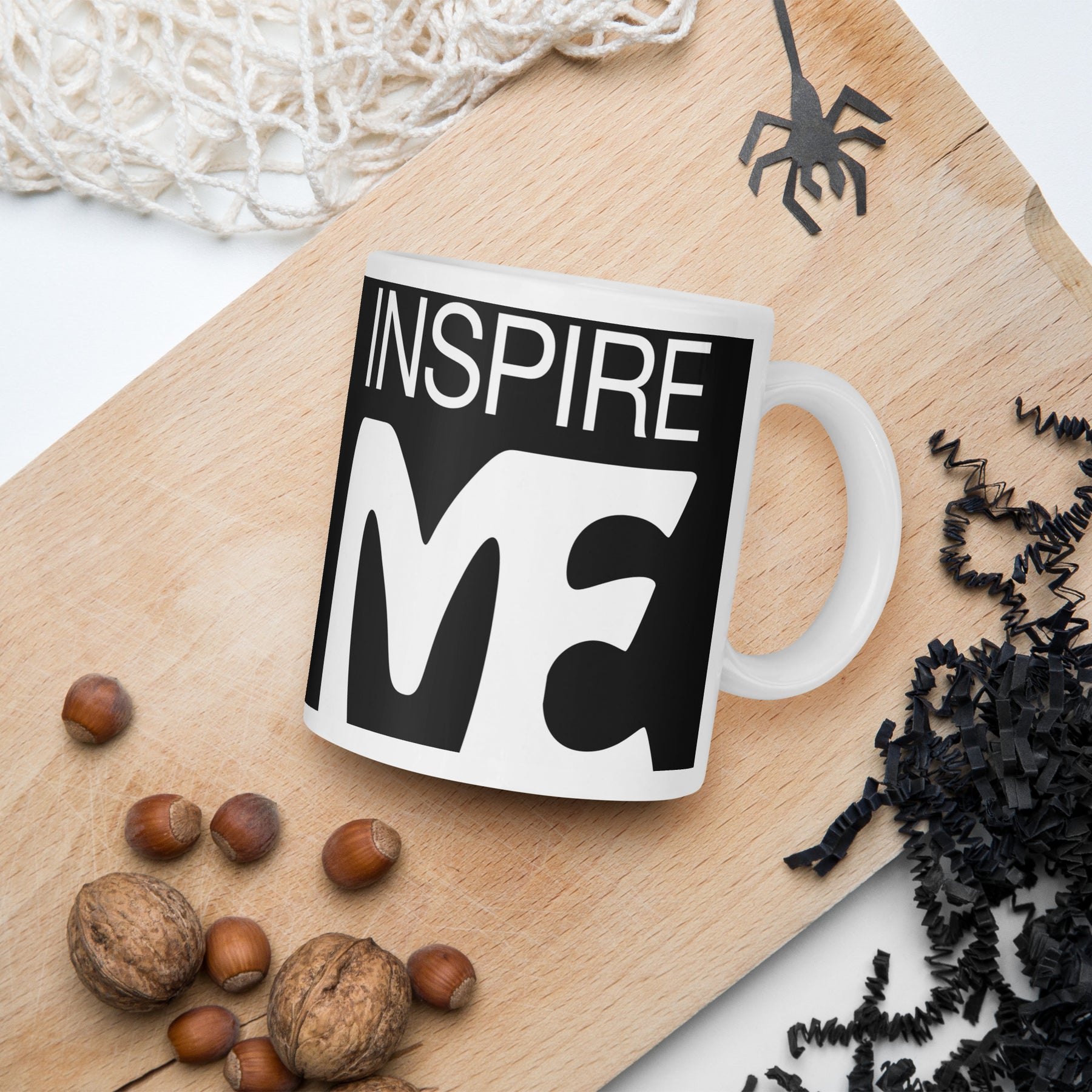 halloween theme view of a black and white mug that says "inspire me" on a cutting board 