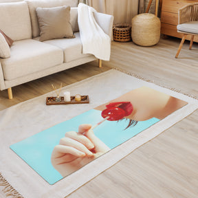 a room view with a yoga mat laying flat on the floor of a girl holding a red lollipop up to her red lips