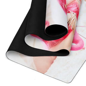 a curled yoga mat on the floor of a girl in a pink wig with pink flamingos